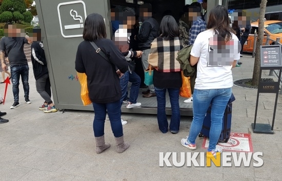 서울 중구의 한 흡연부스. 일부 외국인들이 금연구역표시와 경고안내 문구에도 불구하고 흡연부스 밖에서 버젓히 담배를 피우고 있다.