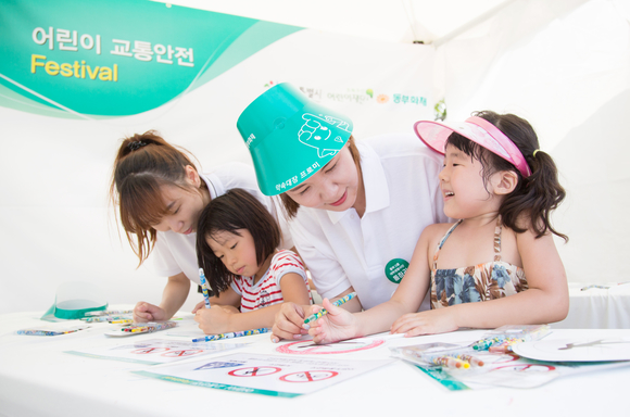 대학생봉사단이 어린이 참가자와 함께 교통표지판 부채그리기를 함께 하고있다 <사진=동부화재 제공>