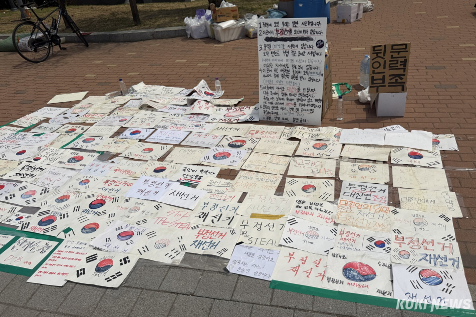 6·3 지방선거 투표용지 부족 사태를 규탄하며 재선거를 요구하는 ‘잠실 개표소 봉쇄 시위’가 계속되고 있는 9일 서울 송파구 올림픽공원 핸드볼경기장 일대에 시민들이 자유롭게 가져가도록 만든 손팻말이 바닥에 놓여 있다. 유병민 기자
